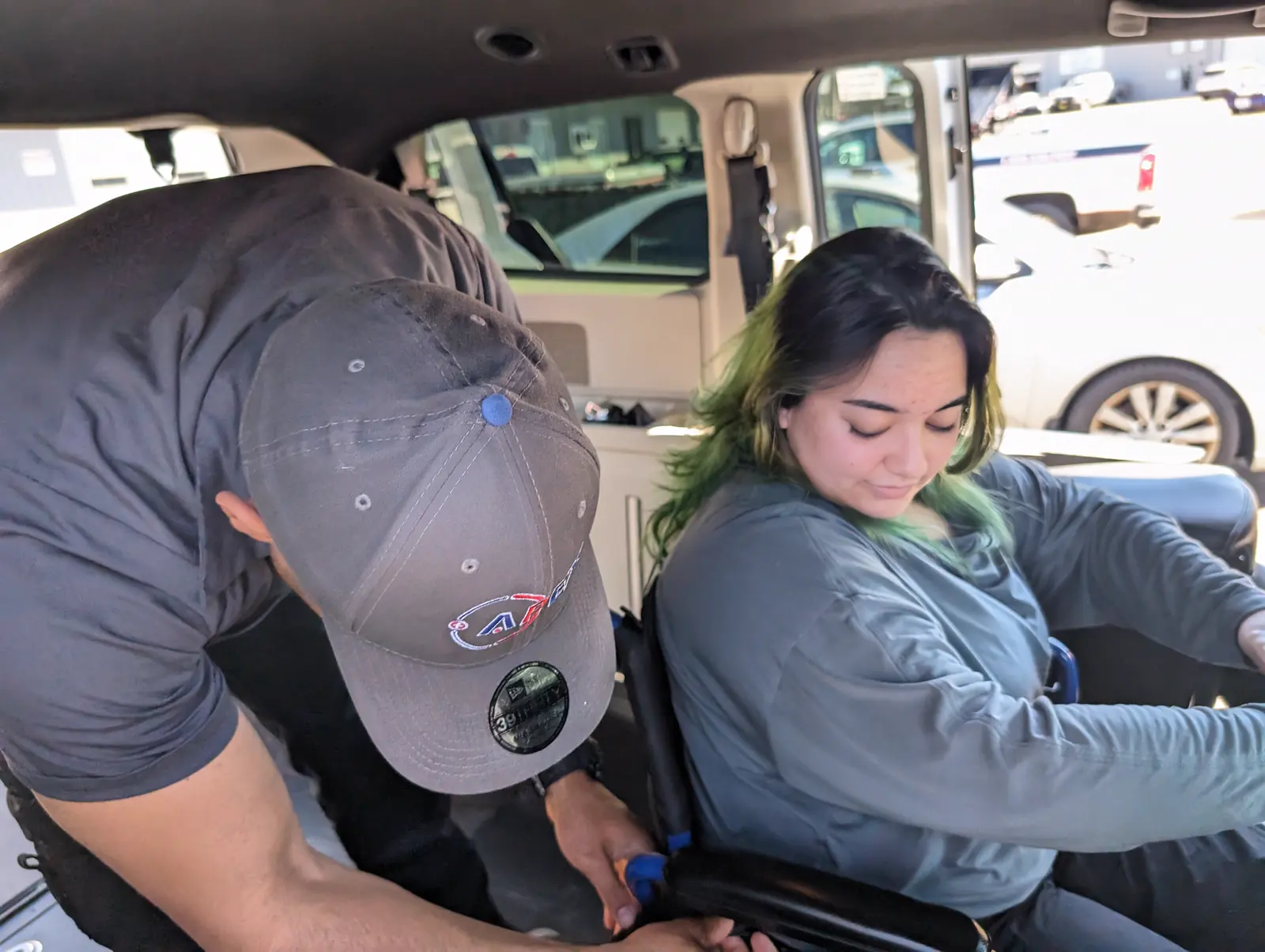 An Apex crew member secures a rider in her wheelchair inside an Apex van