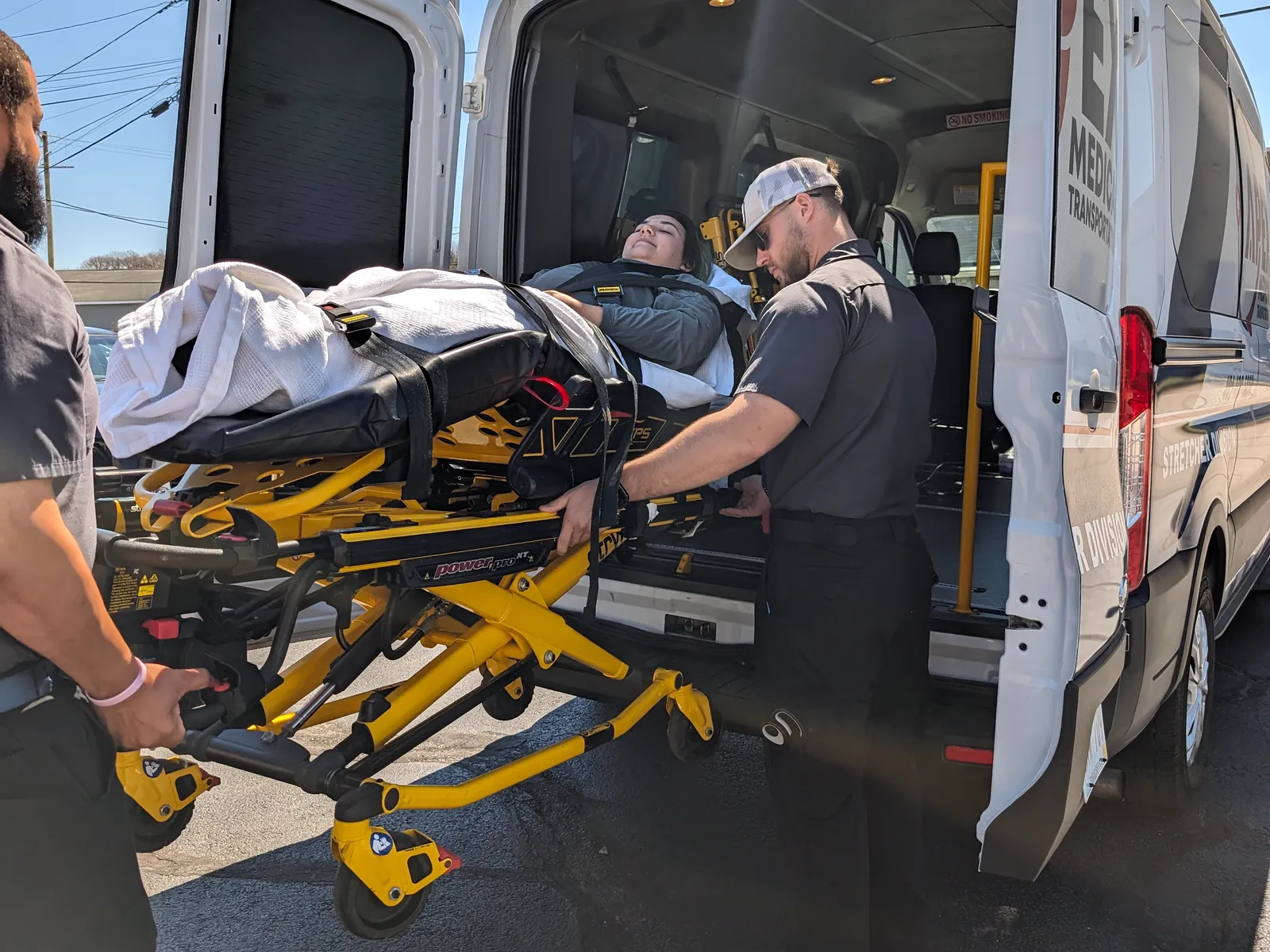 Two Apex crew members load a rider on a stretcher into the back of an Apex van