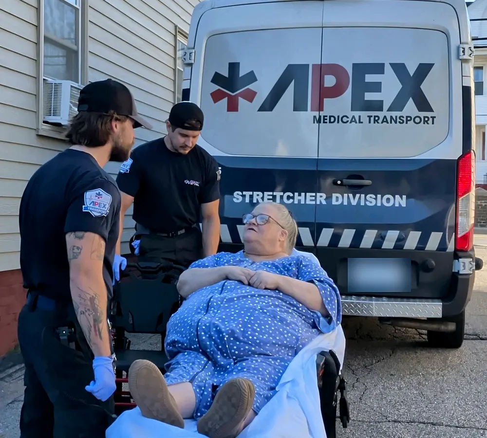 Two Apex crew members with a rider on a stretcher behind an Apex Stretcher Division van